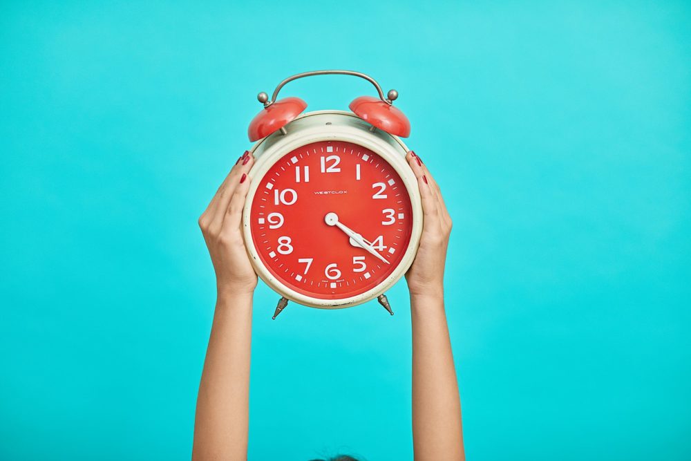 hands holding alarm clock