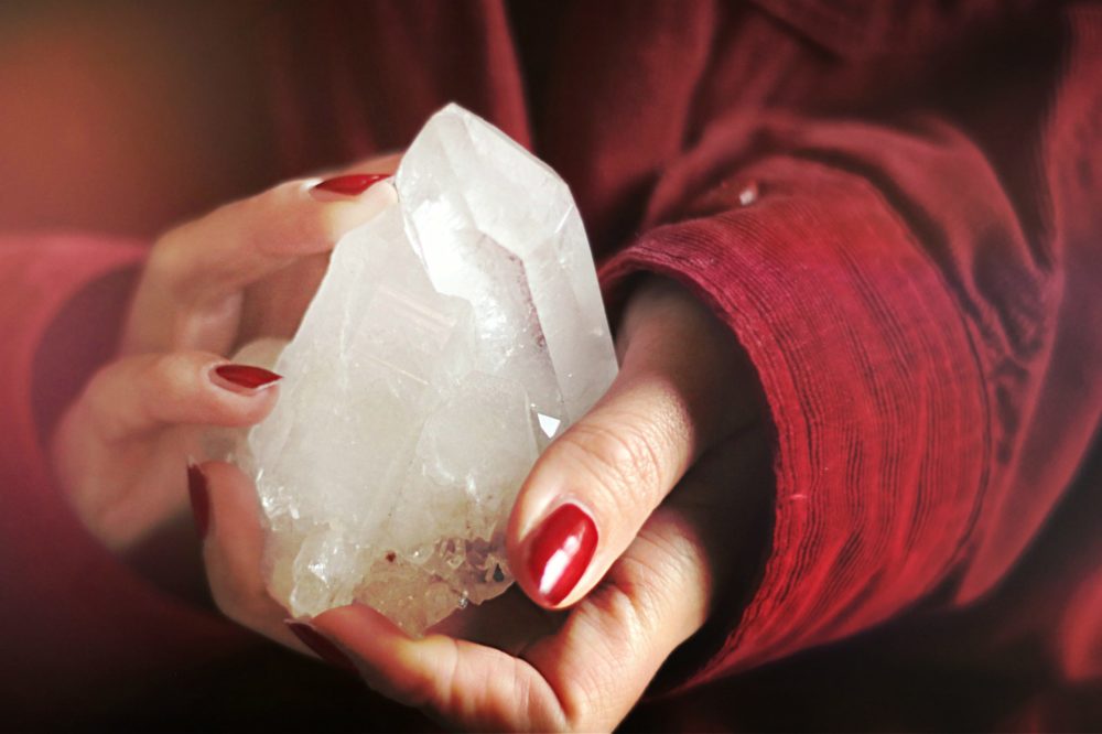 hands holding crystal, red jacket