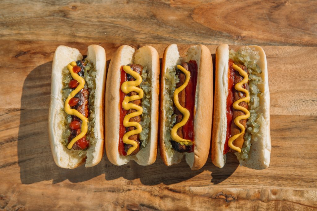 four hot dogs with toppings