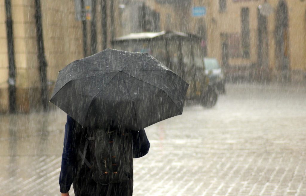 person walking in rain, black umbrella